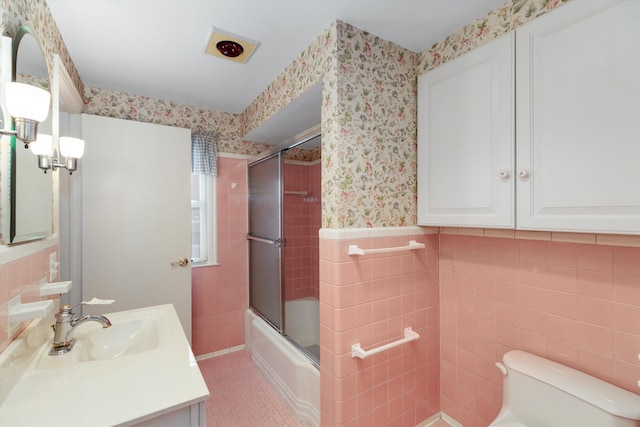 full bathroom with shower / bath combination with glass door, tile walls, vanity, tile patterned floors, and toilet