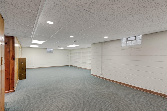 basement featuring a paneled ceiling and dark carpet