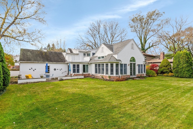 back of property featuring a balcony, a yard, a patio area, and a sunroom