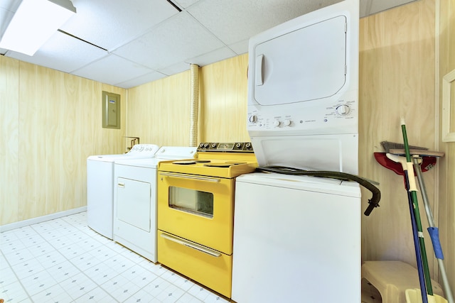 laundry room with stacked washing maching and dryer, electric panel, and wood walls