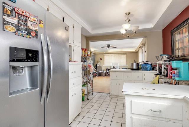 kitchen featuring ceiling fan with notable chandelier, white cabinetry, stainless steel fridge, light tile patterned floors, and a tray ceiling