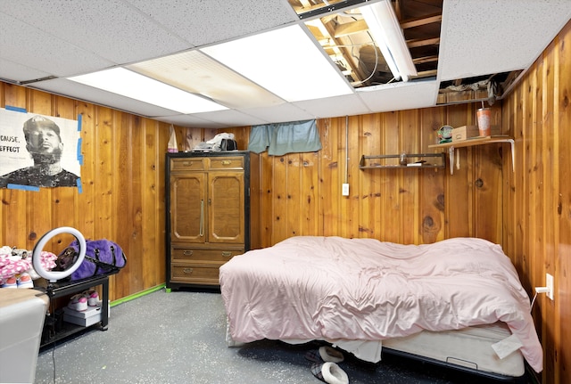 bedroom featuring a paneled ceiling and wooden walls