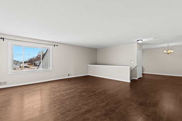 unfurnished living room with dark hardwood / wood-style floors and a notable chandelier