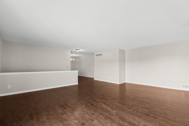 empty room with dark hardwood / wood-style floors and a chandelier