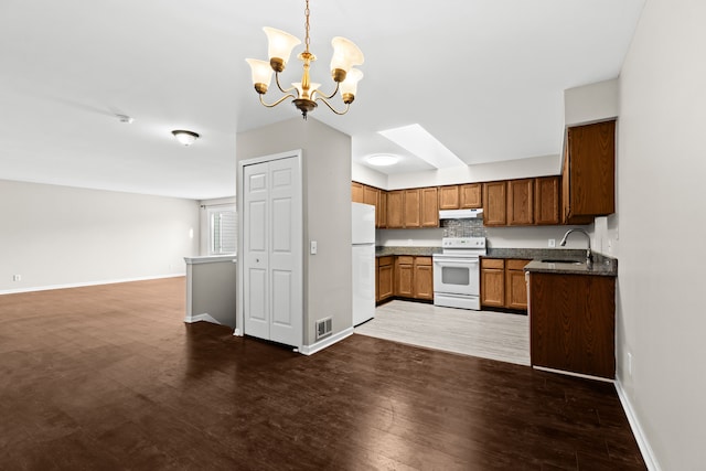 kitchen with pendant lighting, sink, dark hardwood / wood-style flooring, a chandelier, and white appliances