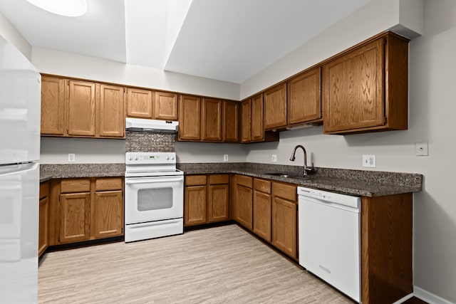 kitchen with white appliances, light hardwood / wood-style floors, sink, and dark stone countertops