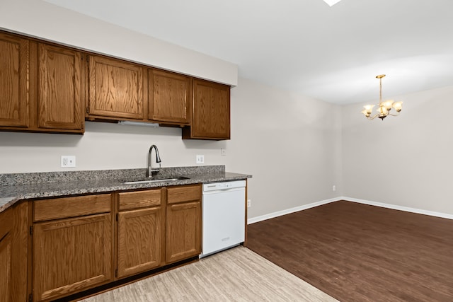 kitchen featuring decorative light fixtures, sink, dark stone counters, white dishwasher, and light wood-type flooring