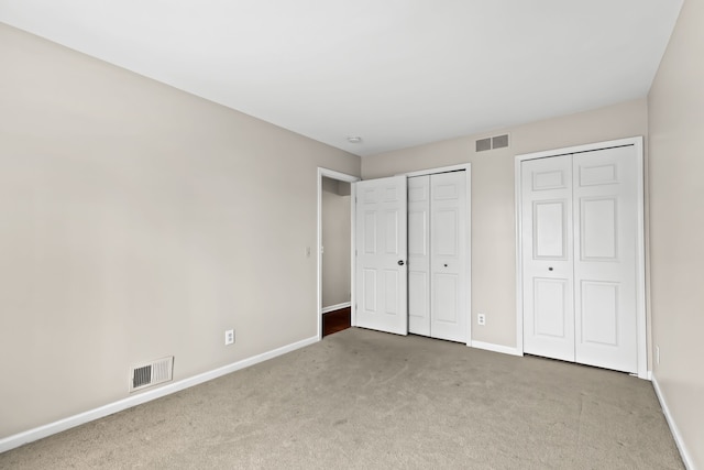 unfurnished bedroom with carpet floors and two closets