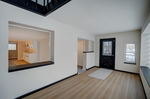 entryway with a textured ceiling and light hardwood / wood-style floors