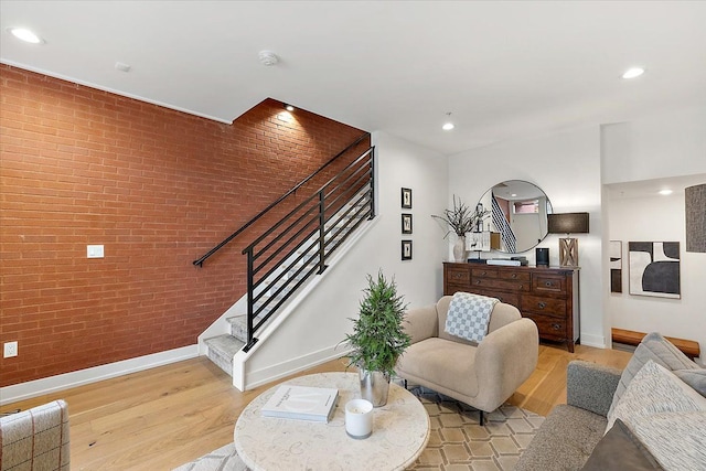 living room with brick wall and light hardwood / wood-style floors