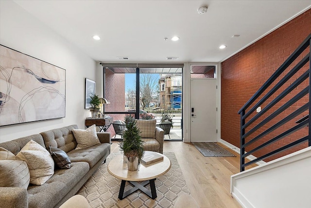 living room with light hardwood / wood-style floors, floor to ceiling windows, and brick wall