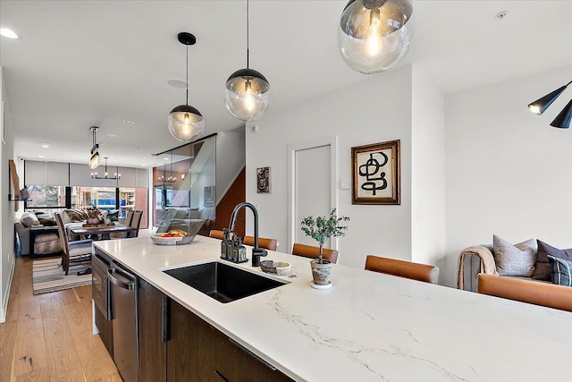 kitchen featuring dishwasher, sink, hanging light fixtures, dark brown cabinetry, and light hardwood / wood-style floors