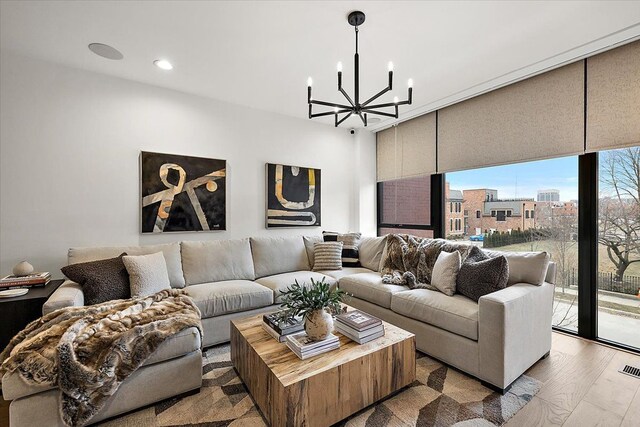 living room featuring an inviting chandelier, floor to ceiling windows, and light hardwood / wood-style flooring