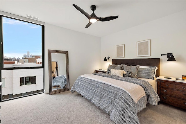 bedroom featuring a wall of windows, light colored carpet, and ceiling fan