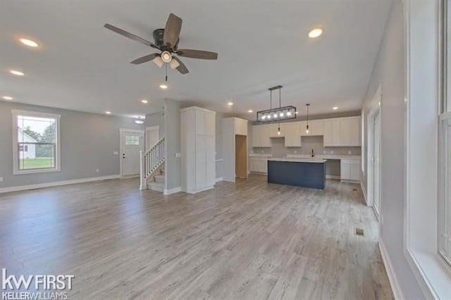 unfurnished living room with ceiling fan, sink, and light hardwood / wood-style floors