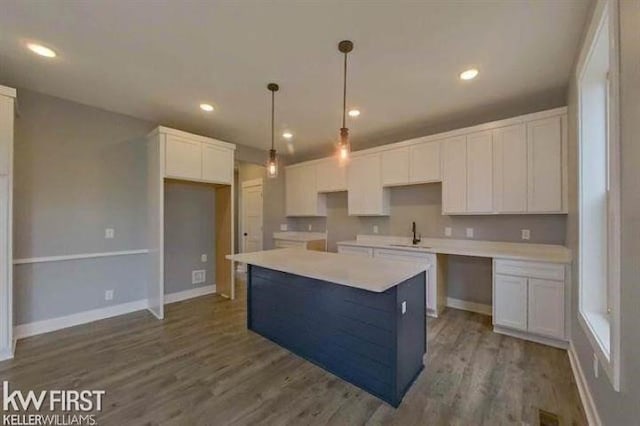 kitchen with hanging light fixtures, sink, white cabinets, and a kitchen island