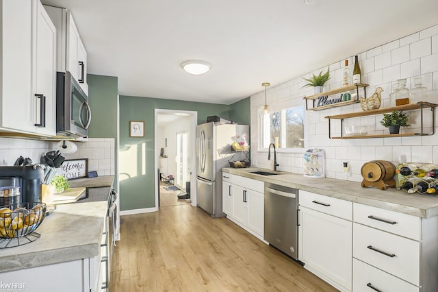 kitchen featuring sink, white cabinetry, decorative light fixtures, stainless steel appliances, and backsplash