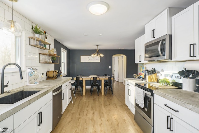 kitchen featuring pendant lighting, stainless steel appliances, sink, and white cabinets