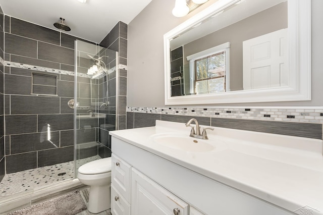 bathroom featuring tile walls, vanity, toilet, and tiled shower