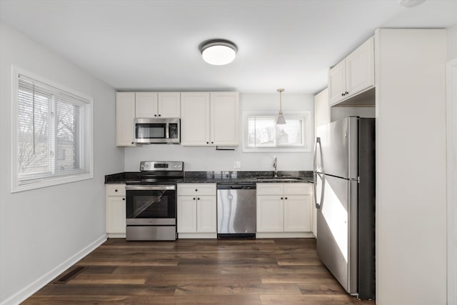 kitchen with sink, white cabinets, dark hardwood / wood-style flooring, hanging light fixtures, and stainless steel appliances