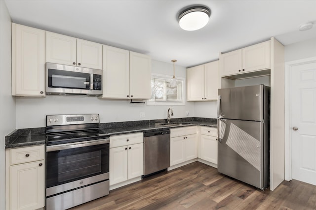 kitchen with sink, appliances with stainless steel finishes, hanging light fixtures, dark hardwood / wood-style floors, and white cabinets