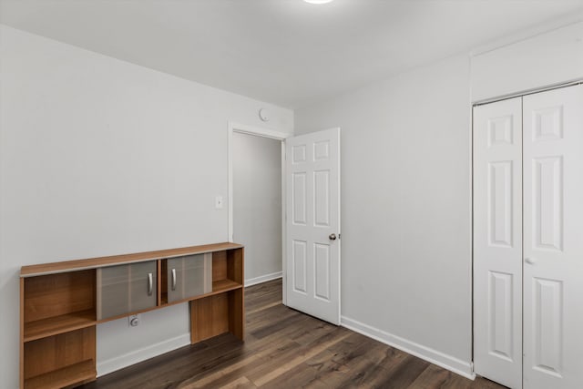 unfurnished bedroom with dark wood-type flooring and a closet