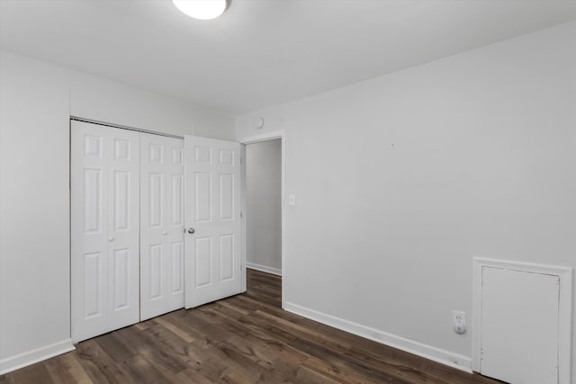 unfurnished bedroom with dark hardwood / wood-style flooring and a closet