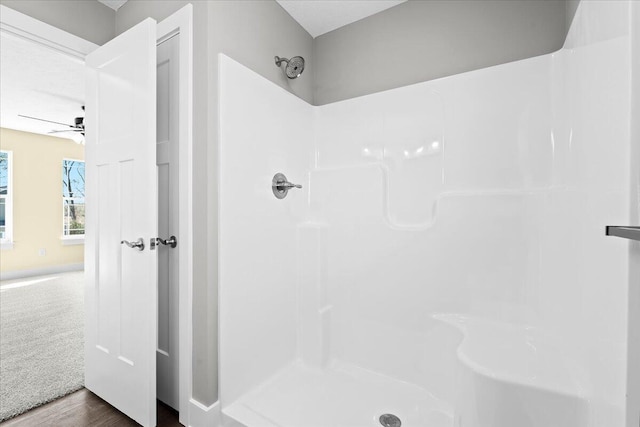 bathroom with hardwood / wood-style floors, ceiling fan, and walk in shower