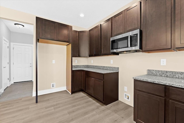 kitchen with light stone counters, light hardwood / wood-style flooring, and dark brown cabinetry