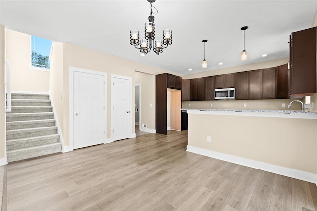 kitchen with light hardwood / wood-style floors, sink, dark brown cabinetry, and decorative light fixtures