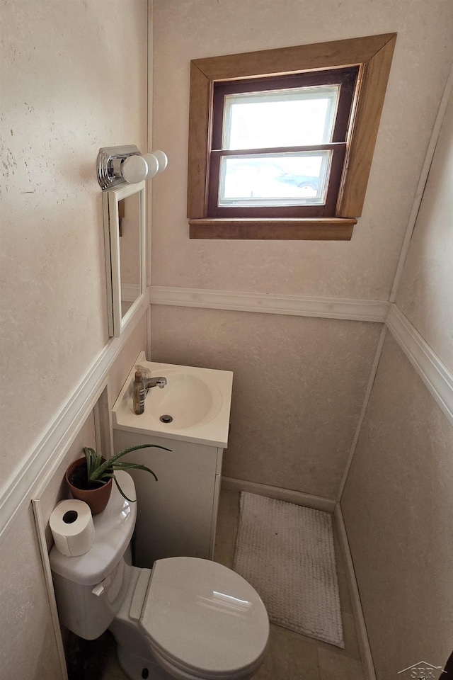 bathroom featuring toilet, a wainscoted wall, and vanity