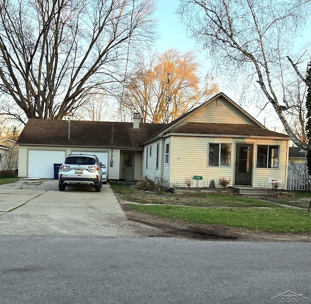 view of front of home with an attached garage, a front lawn, a chimney, and concrete driveway