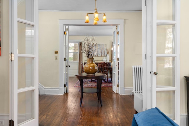 doorway to outside with dark hardwood / wood-style floors, radiator, and an inviting chandelier