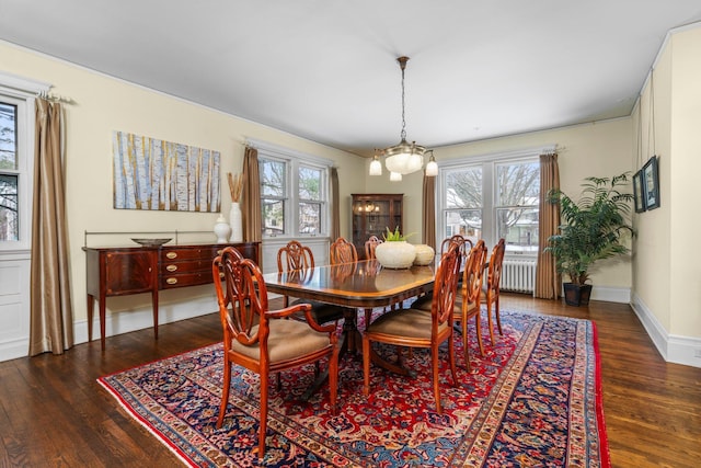 dining space featuring radiator, dark wood-type flooring, and a chandelier