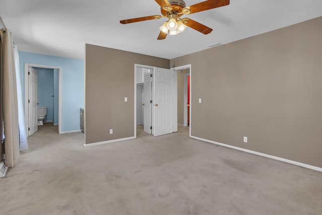 unfurnished bedroom with connected bathroom, a spacious closet, ceiling fan, light carpet, and a closet