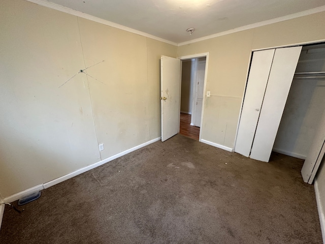 unfurnished bedroom featuring crown molding, dark carpet, and a closet