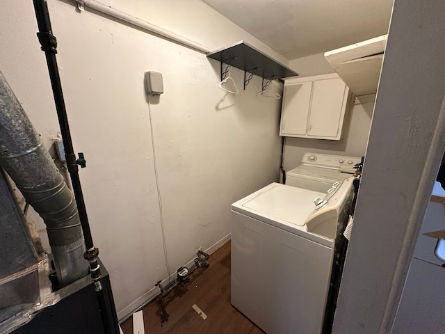 clothes washing area with cabinets, dark wood-type flooring, and washing machine and clothes dryer