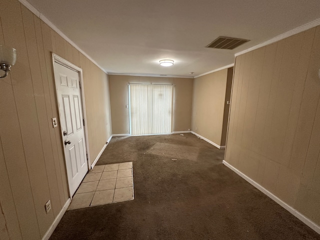 empty room with carpet flooring, ornamental molding, and wooden walls