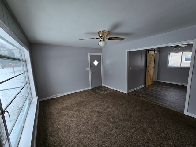 interior space with ceiling fan, a barn door, dark carpet, and a closet