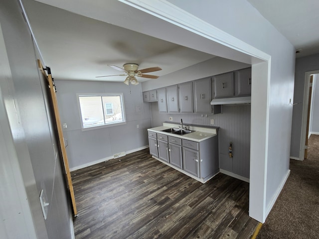 kitchen featuring sink, gray cabinetry, dark hardwood / wood-style flooring, ceiling fan, and a barn door