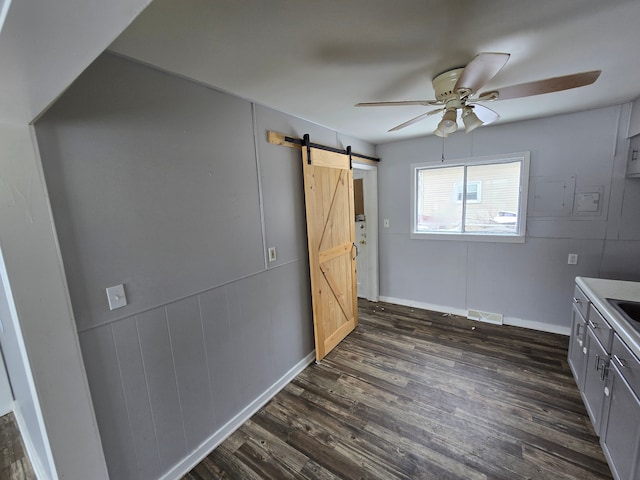 interior space with a barn door, dark hardwood / wood-style floors, and ceiling fan