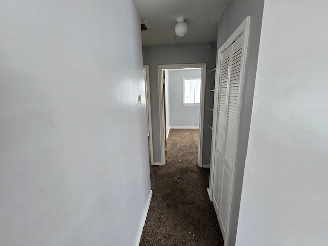 hallway featuring carpet and baseboards
