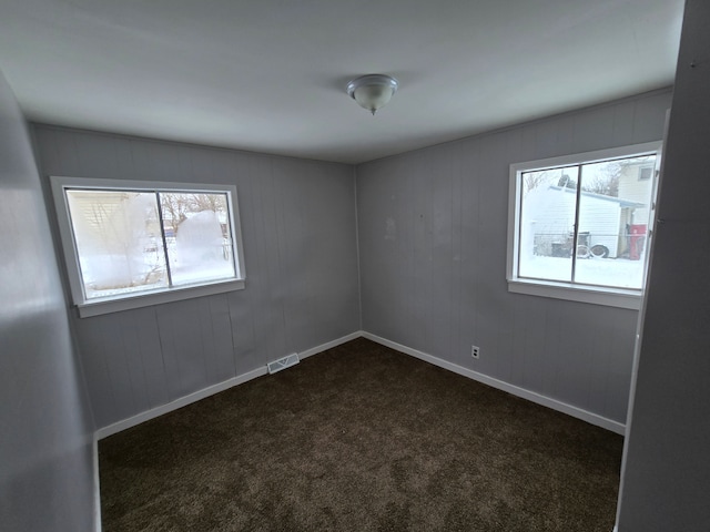 spare room with baseboards, visible vents, and dark carpet