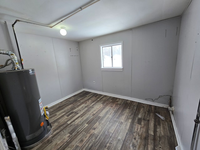 spare room with gas water heater and dark hardwood / wood-style floors