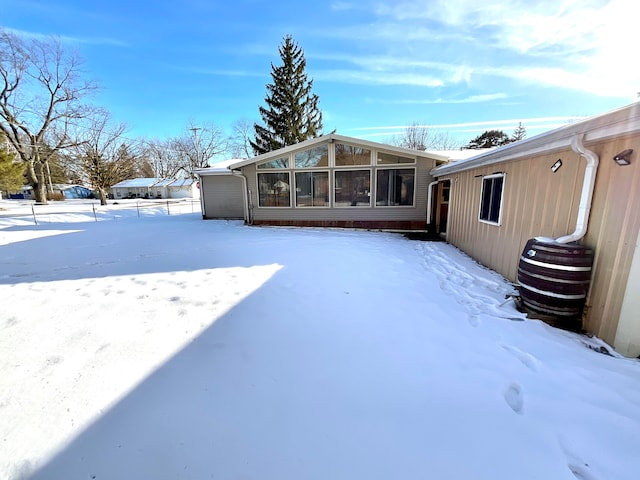 snow covered house featuring a sunroom