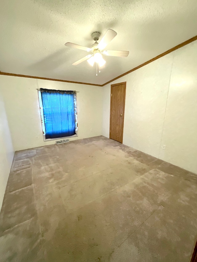 carpeted spare room featuring ceiling fan, ornamental molding, and a textured ceiling