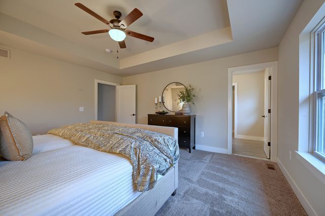 carpeted bedroom featuring a tray ceiling and ceiling fan