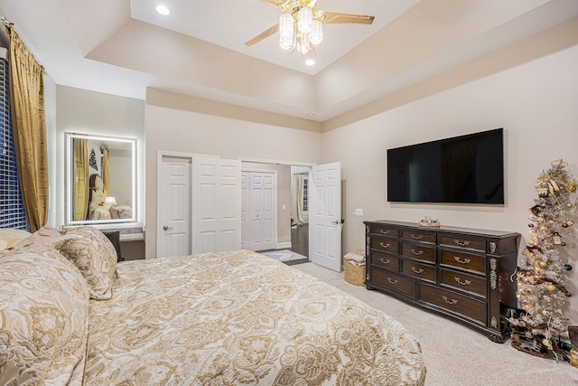 carpeted bedroom featuring multiple closets, ceiling fan, a raised ceiling, and a towering ceiling