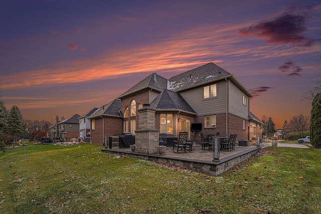 back house at dusk with a yard and a patio area