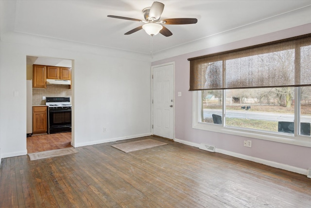 unfurnished living room featuring dark wood-type flooring and ceiling fan